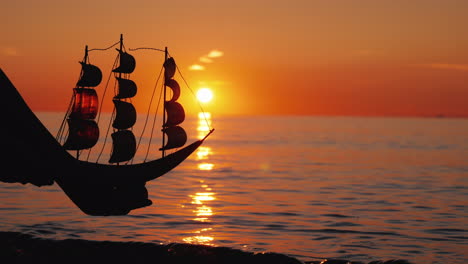 Hands-Holding-A-Toy-Sailboat-Over-The-Waves-At-Sunset-The-New-Initiative-Concept