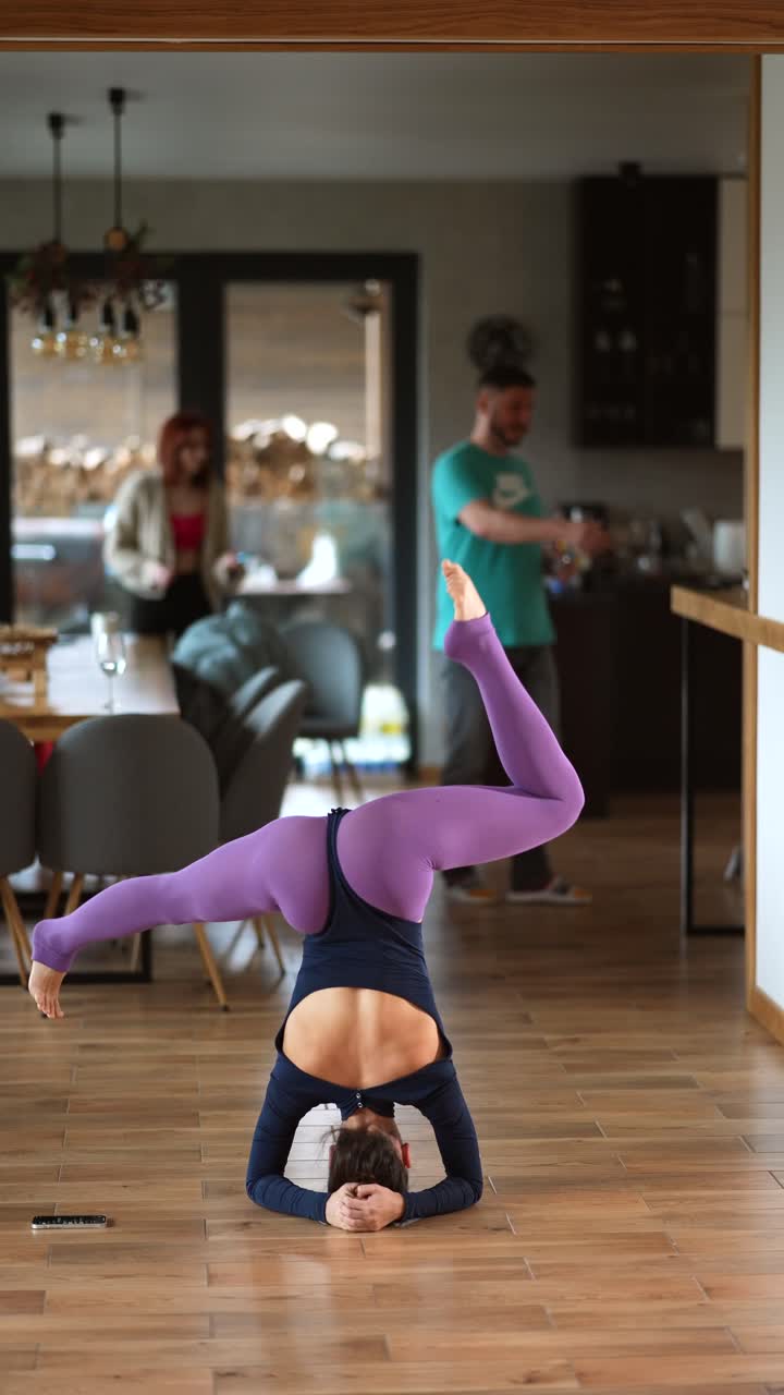 mujer haciendo un headstand en una cocina de casa