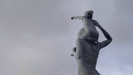 bronze statue of mother carrying child on shoulders