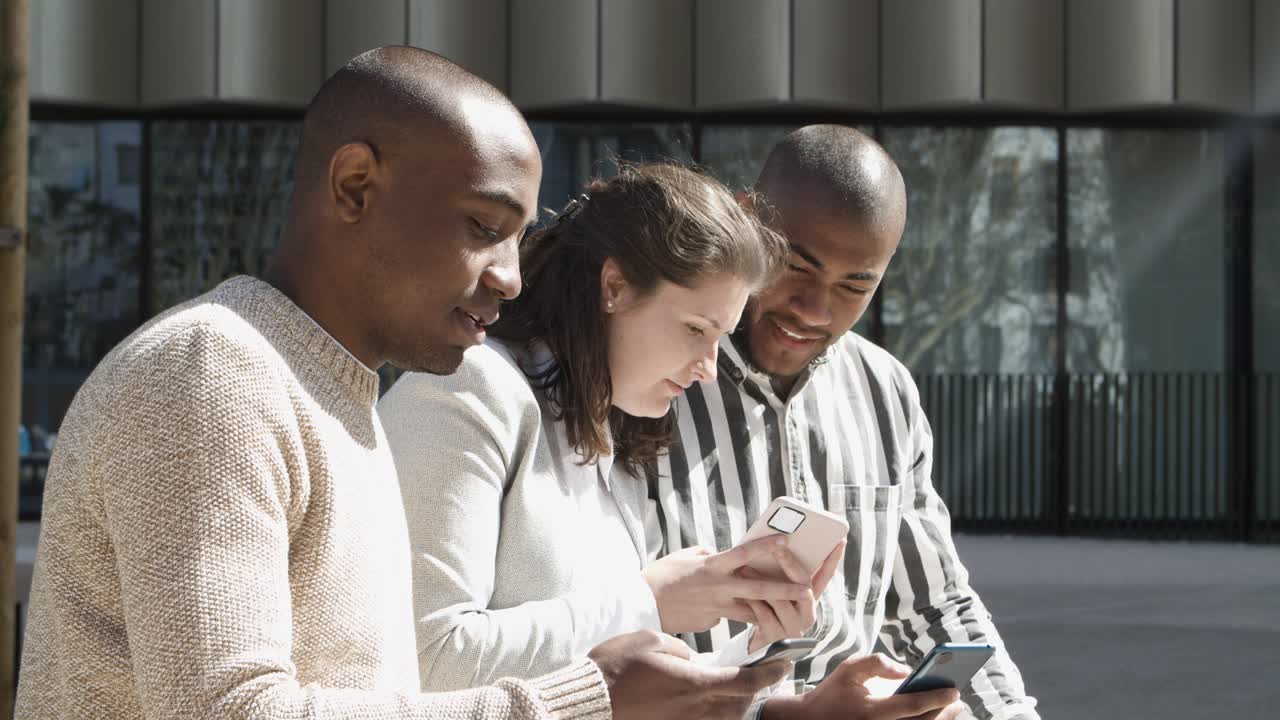 Cheerful friends talking and using smartphones