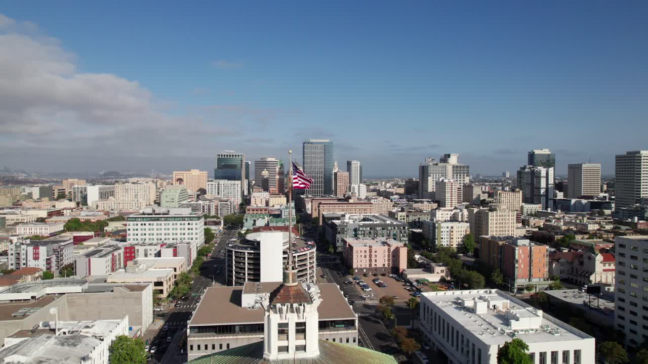 Panorama of Oakland, California skyline with courthouse and United States Flag in foreground, 4K aerial footage