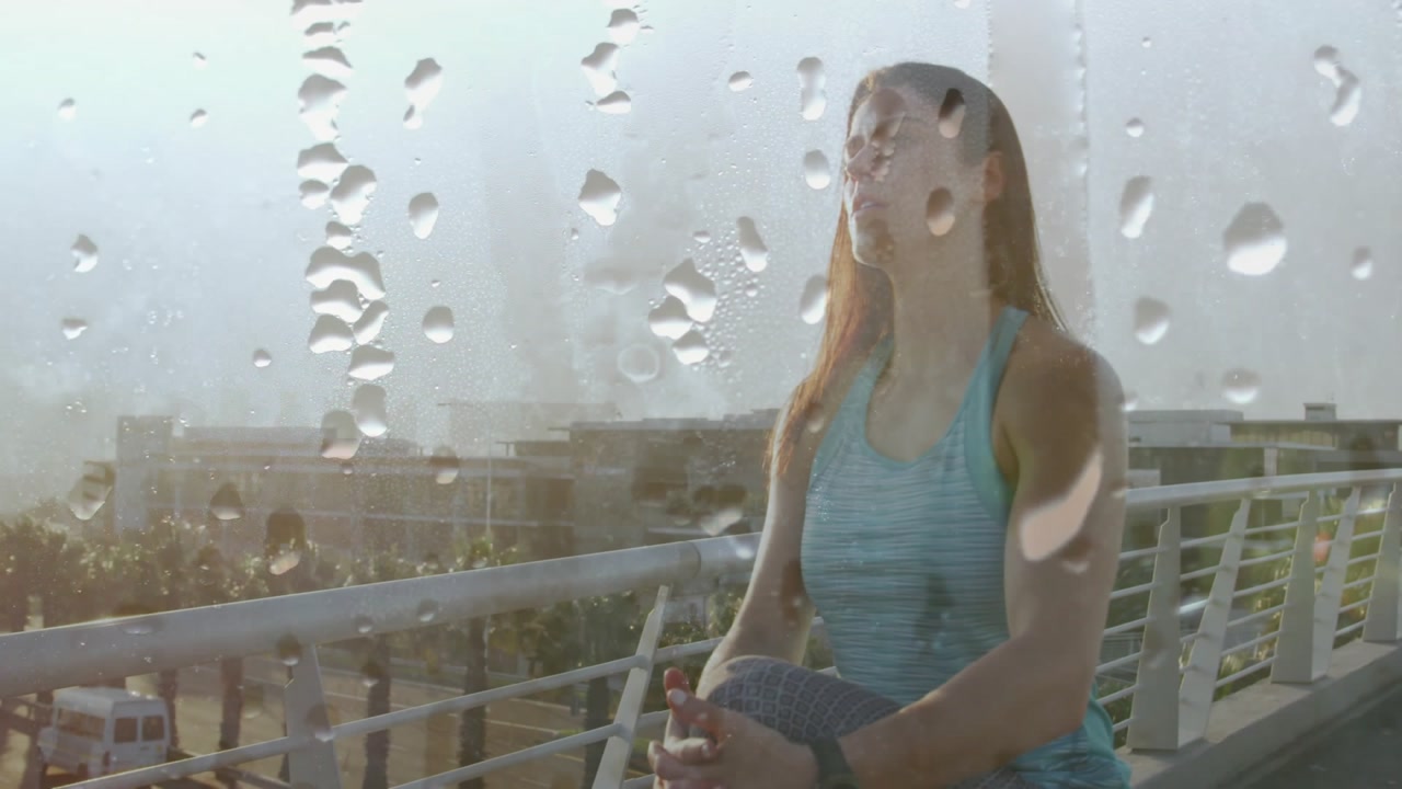 Female athlete stretching knee on railing while animated health data chart floating over raindrops