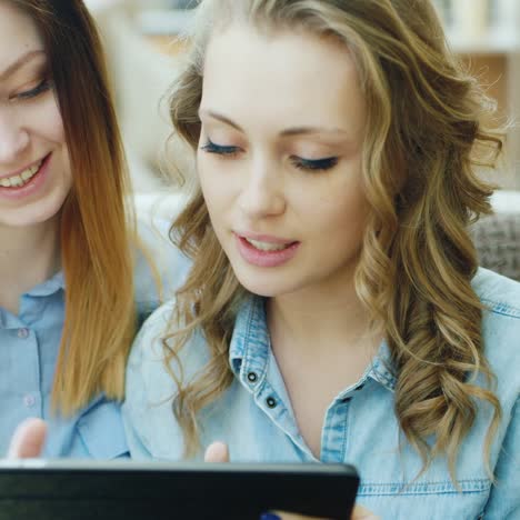 two friends relax in a cafe looking at the tablet screen