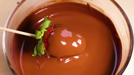 strawberry being dipped in melted chocolate