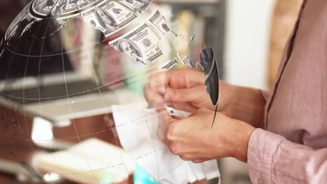 digital composite video of globe made of american dollar bills against woman sewing face mask