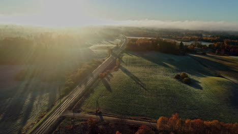 Aerial-flyover-frozen-rural-landscape-in-the-morning-with-fields-and-forest-in-sunlight