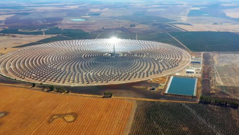 solar panels in a large thermal circular power plant with the reflection of the sunlight in the panels. renewable and pollution-free energy in a solar farm in spain- aerial view with a drone - environmental concept