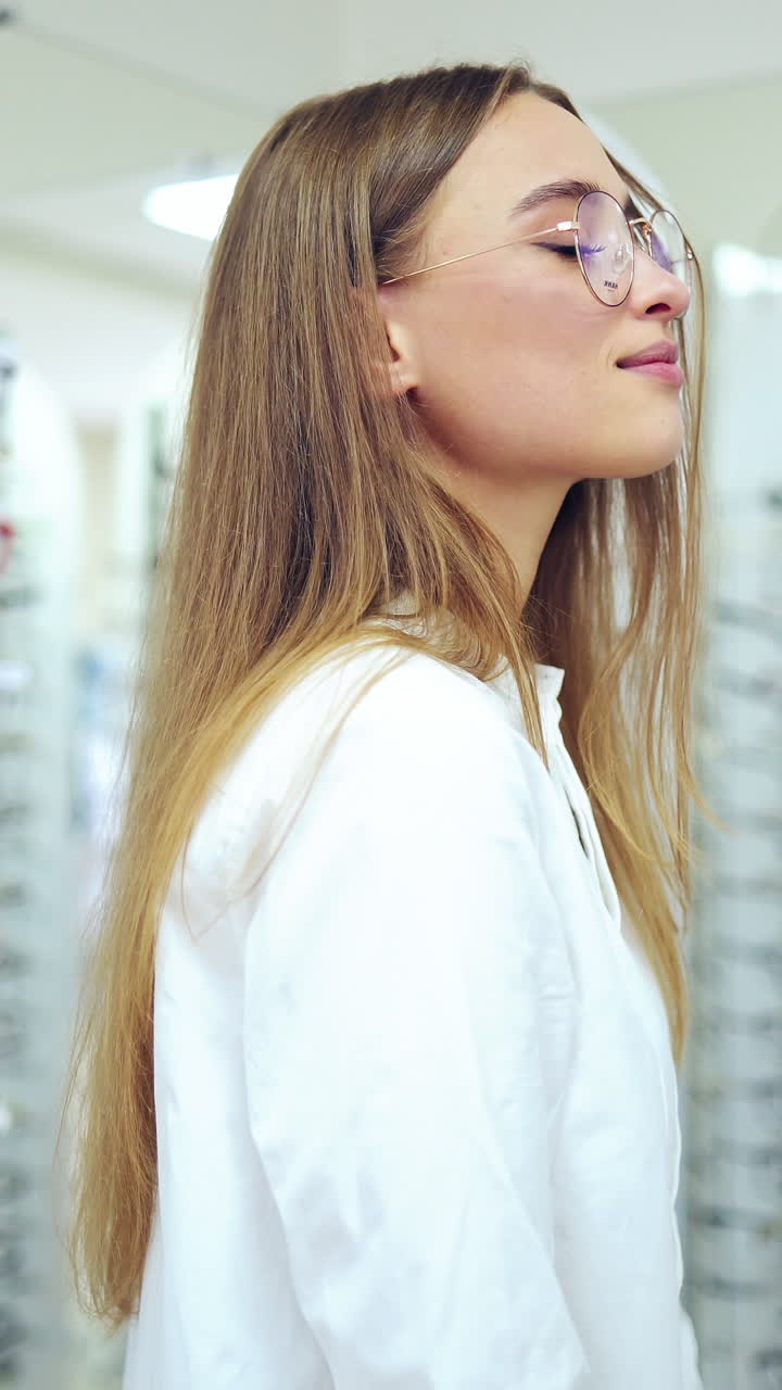 Smiling woman in new eyeglasses. Happy young female buyer choosing stylish spectacles at optical shop. Healthy eyesight. Vertical video