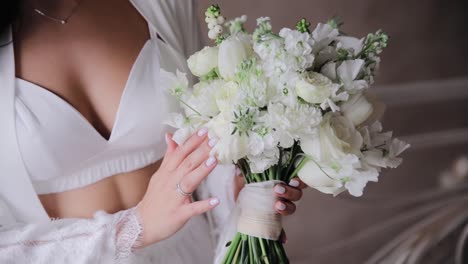 Charming-bride-in-a-white-top-holding-a-wedding-bouquet-of-white-roses,-tulips-and-other-flowers