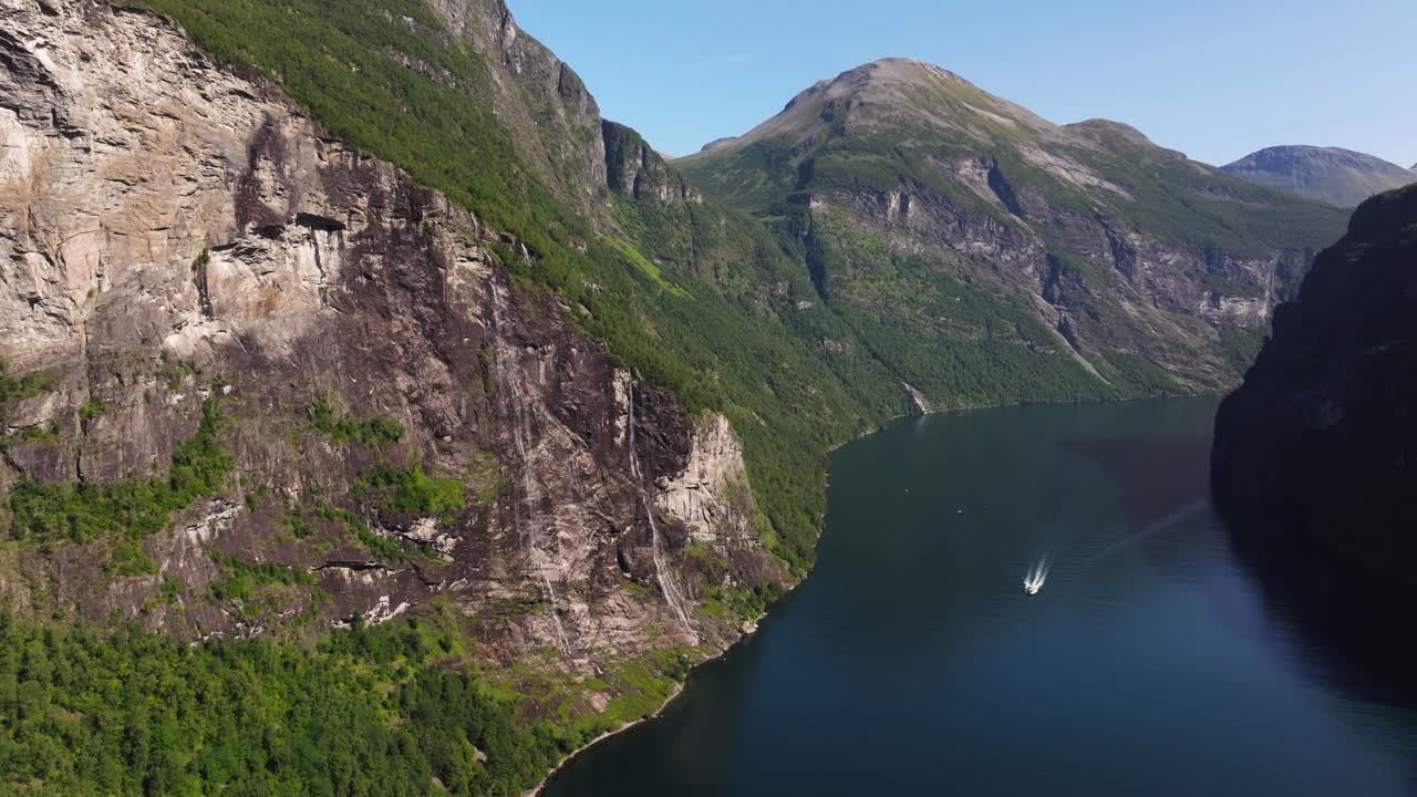 drone volando lejos de la cascada de las siete hermanas en noruega mientras el ferry pasa por debajo