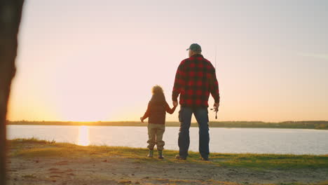 cute toddler and his grandfather are amazing beautiful sunset on river or lake old man and grandson