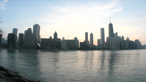 lake michigan reflects the chicago skyline as evening darkens into a colorful sky