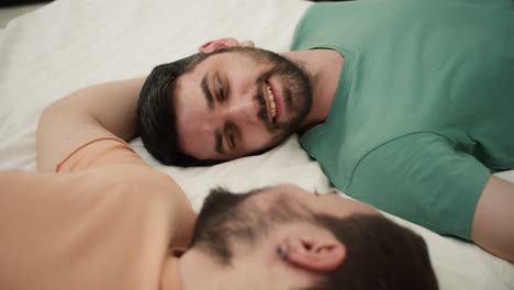 portrait of attractive bearded gay men couples lying on bed together, touching face with romantic feeling