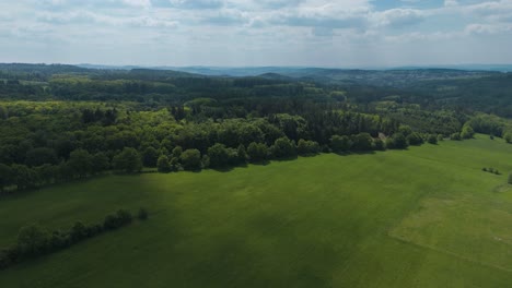 Aerial-view-of-bohemian-meadows-and-broadleaved-forests-with-hills-in-the-background