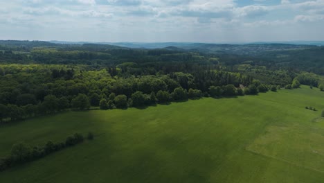 aerial view of bohemian meadows and broadleaved forests with hills in the background