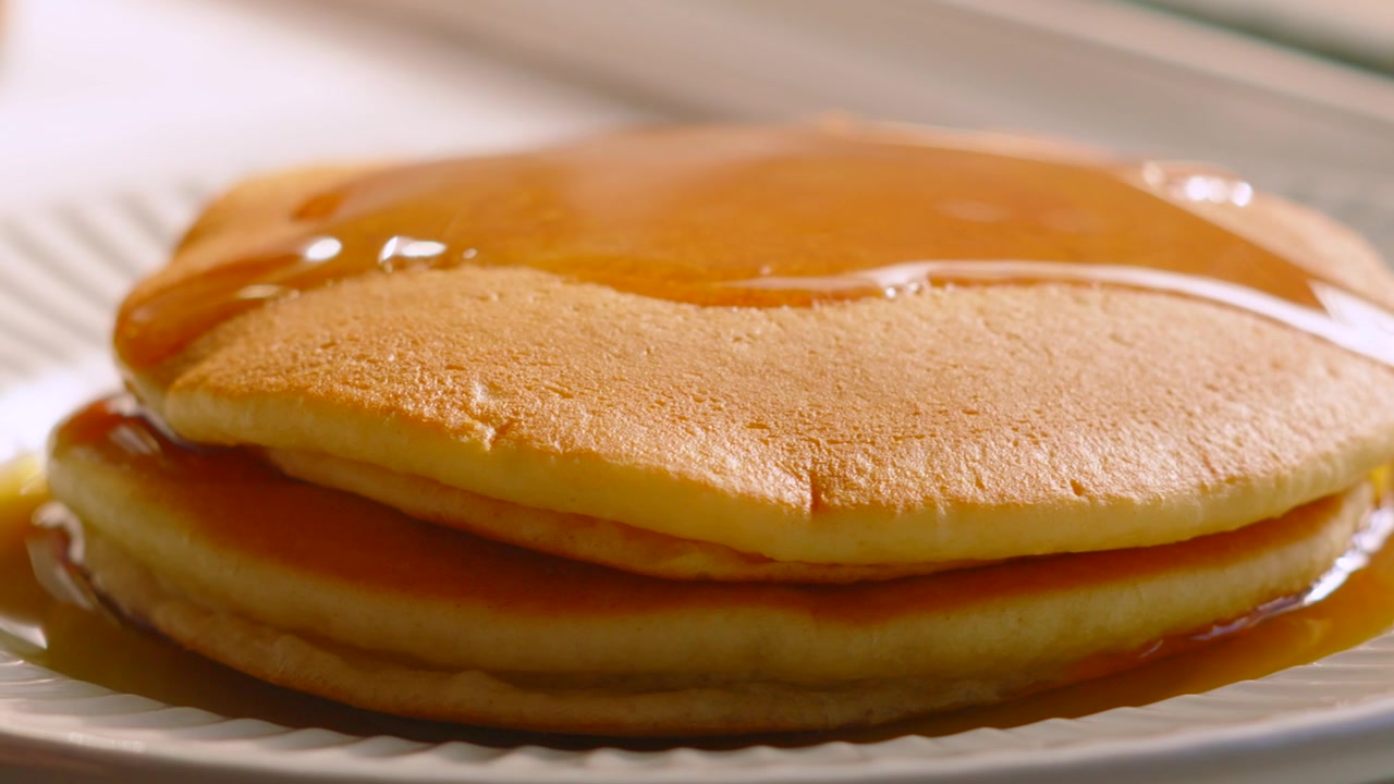 Soft Buttermilk Pancakes Covered in Maple Syrup with Golden Gooey Shine. Indulgent Breakfast Food.