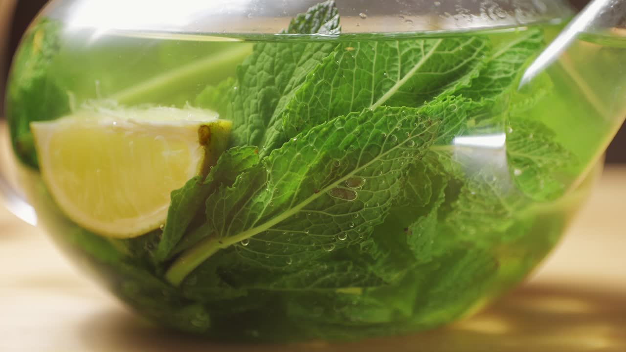 Teapot of fresh mint moroccan tea with lime, tea pot close up with pouring boiling water.