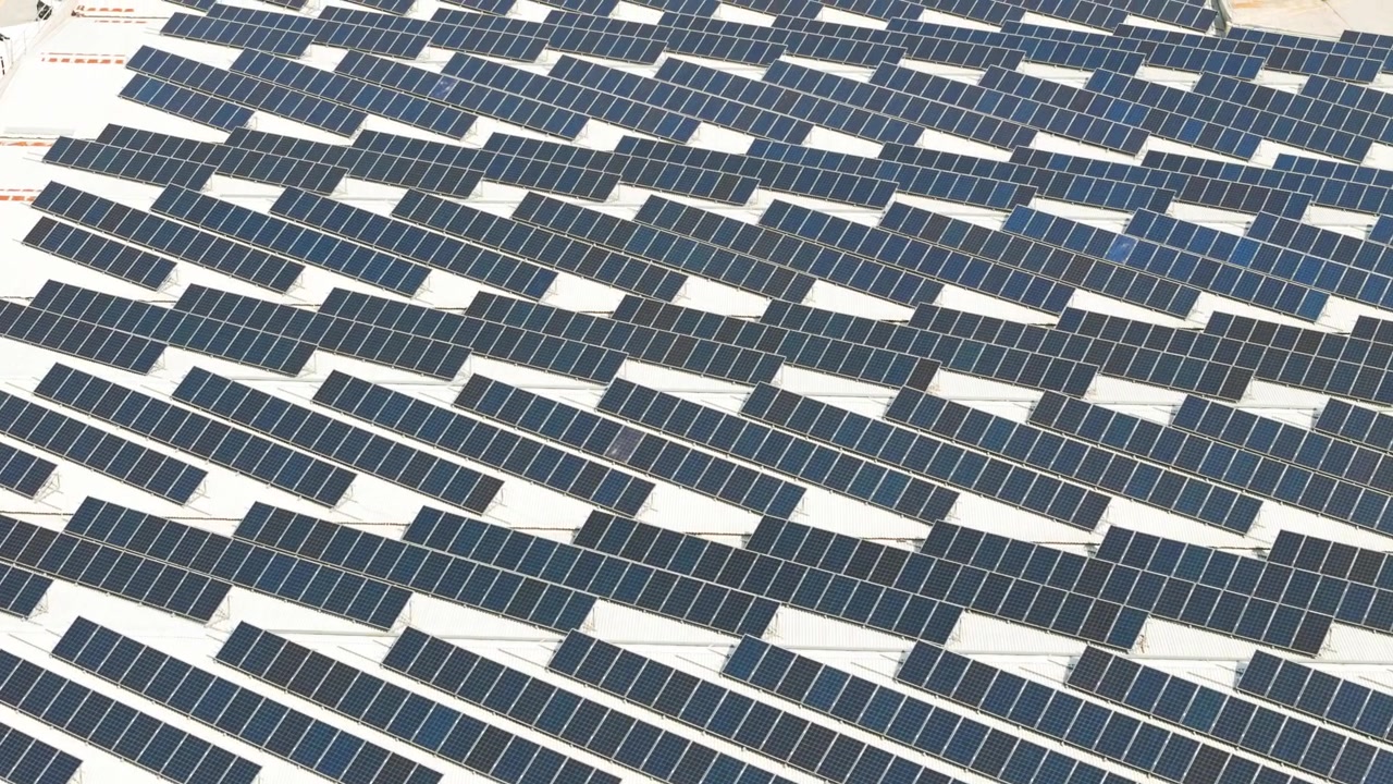 Vista aerea che mostra un'enorme installazione di pannelli solari sul tetto di un edificio moderno, che rappresenta una fonte di energia verde sostenibile.