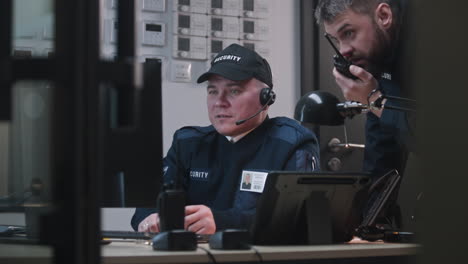 two security guards monitoring surveillance in a control room