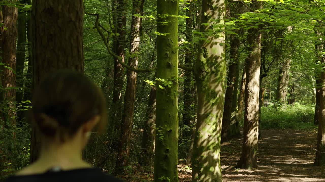 산책로 를 가진 울불 한 자연 숲 을 고 있는 차분 한 여성 이 선글라스 를 착용 하고 있다