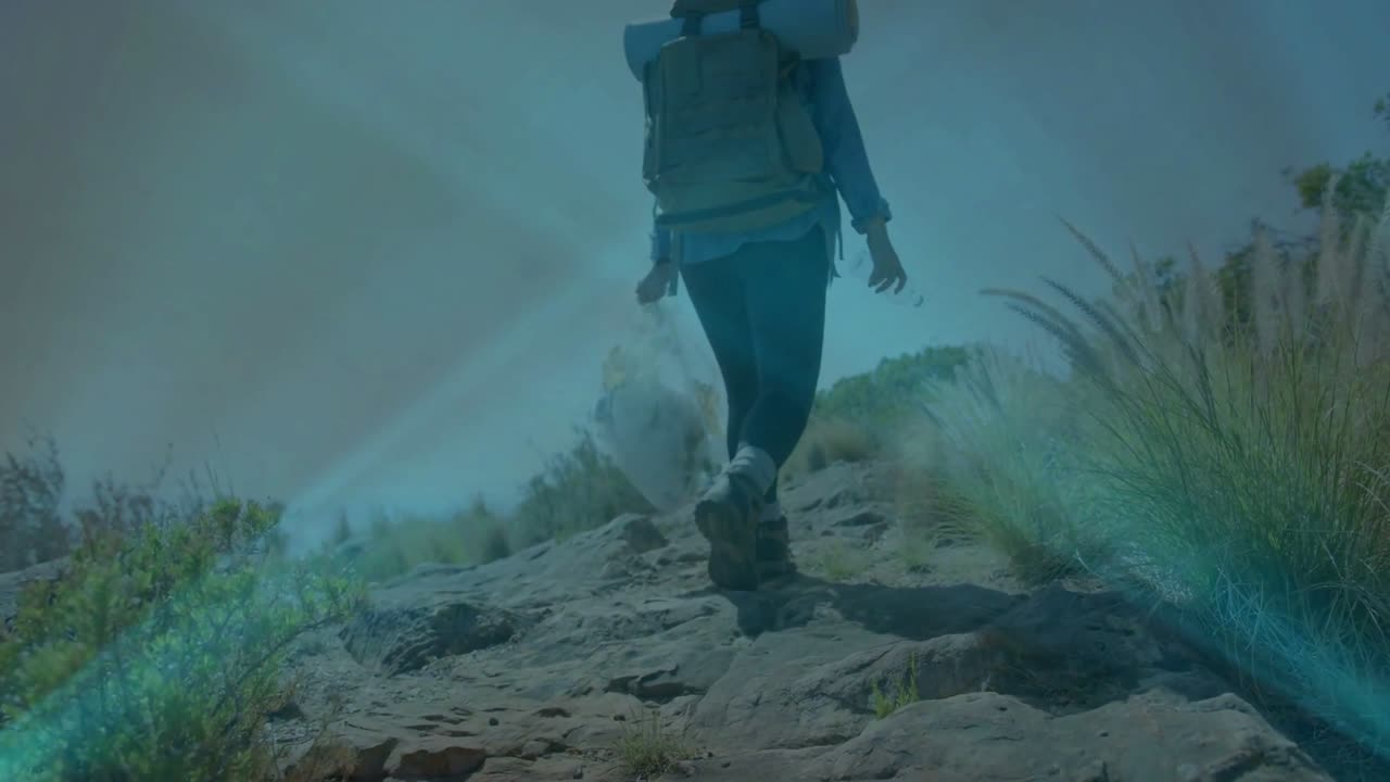 Female hiker initiating ascent and walking uphill on outdoor hike, teal overlay accenting pack dust