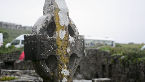 vieja lápida en forma de cruz bajo la lluvia en un cementerio cerca