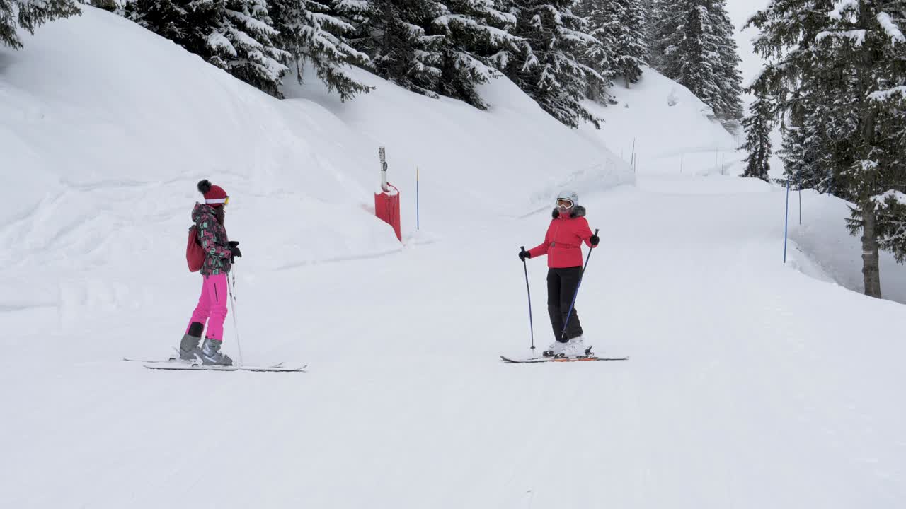 лыжники, стоящие на склоне, показывают друг другу маршрут, где кататься на лыжах