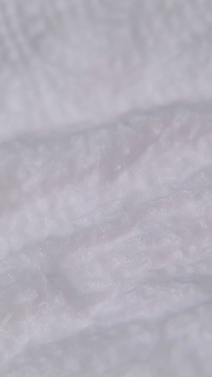 spraying clean liquid from white thin plastic tube onto white paper napkin extreme close view