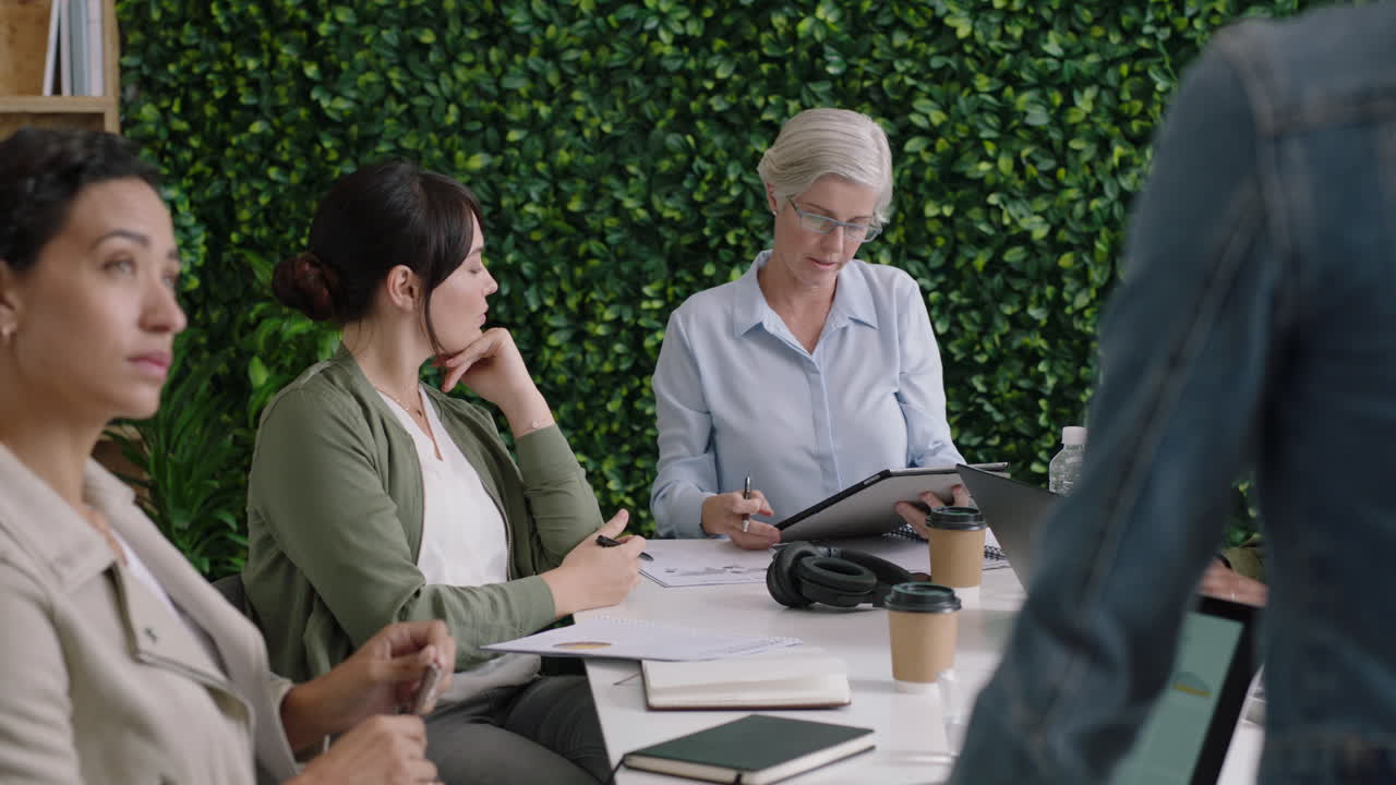 전문 사업가들이 모여 브레인스토밍을 하고 여성 리더가 금융 프로젝트에 대한 창의적인 아이디어를 공유하고 다민족 팀이 함께 일하고 사무실 회의실에서 협력하고 팀워크를 즐기고 있습니다.