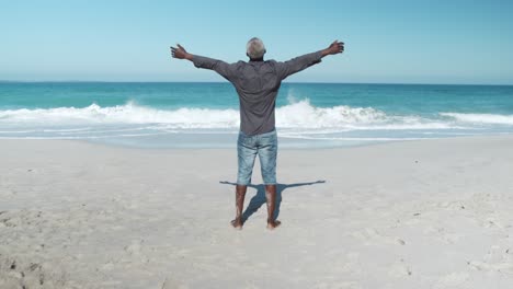 senior man raising his arms at the beach