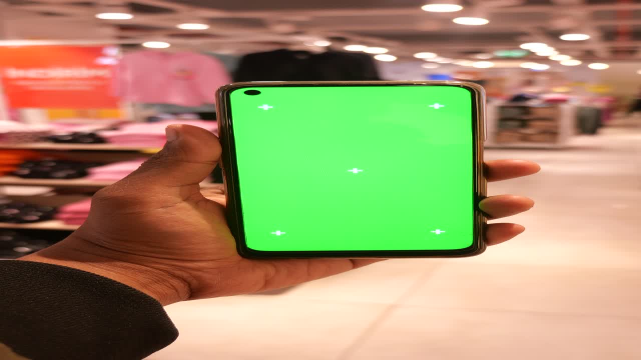 Persona che tiene uno smartphone con green screen