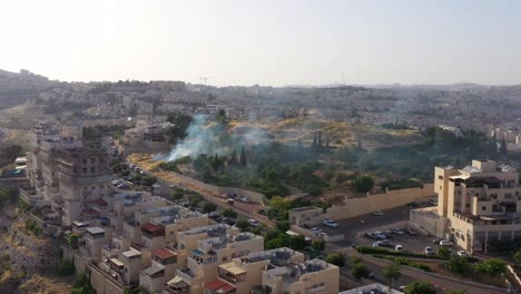 aerial view of smoke rising from a hillside in a residential city area