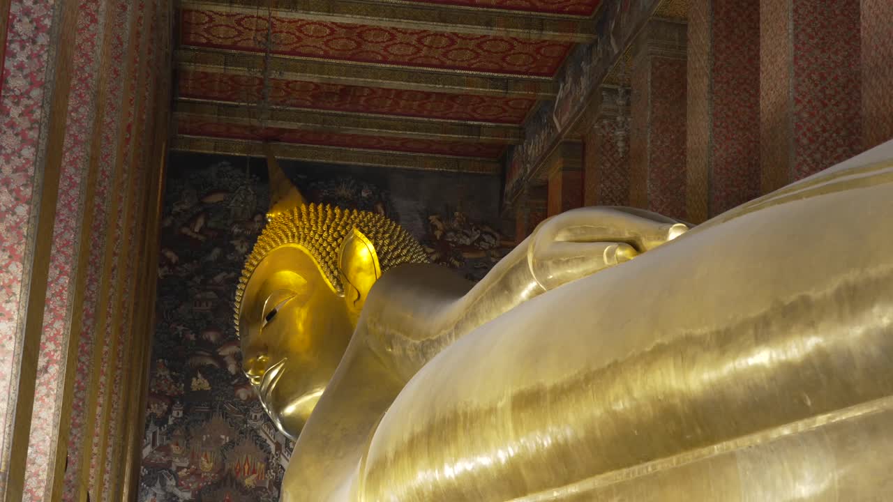 Reclining Buddha statue with a glittering gold finish, depicting the path to Nirvana in its final earthly form, found within the sacred temple of Wat Pho in Bangkok, Thailand