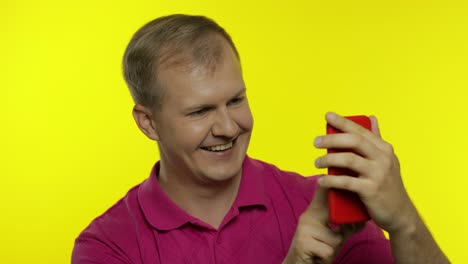 young man posing in pink t-shirt. handsome guy using mobile phone, watching funny videos online