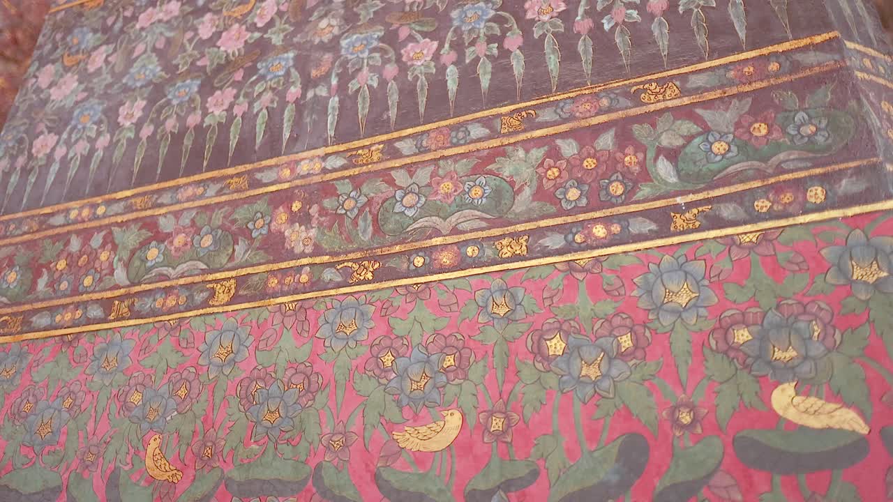 video detallado de las pinturas ornamentadas en la pared de wat pho, que muestran colores vibrantes y patrones intrincados en un entorno sereno del templo