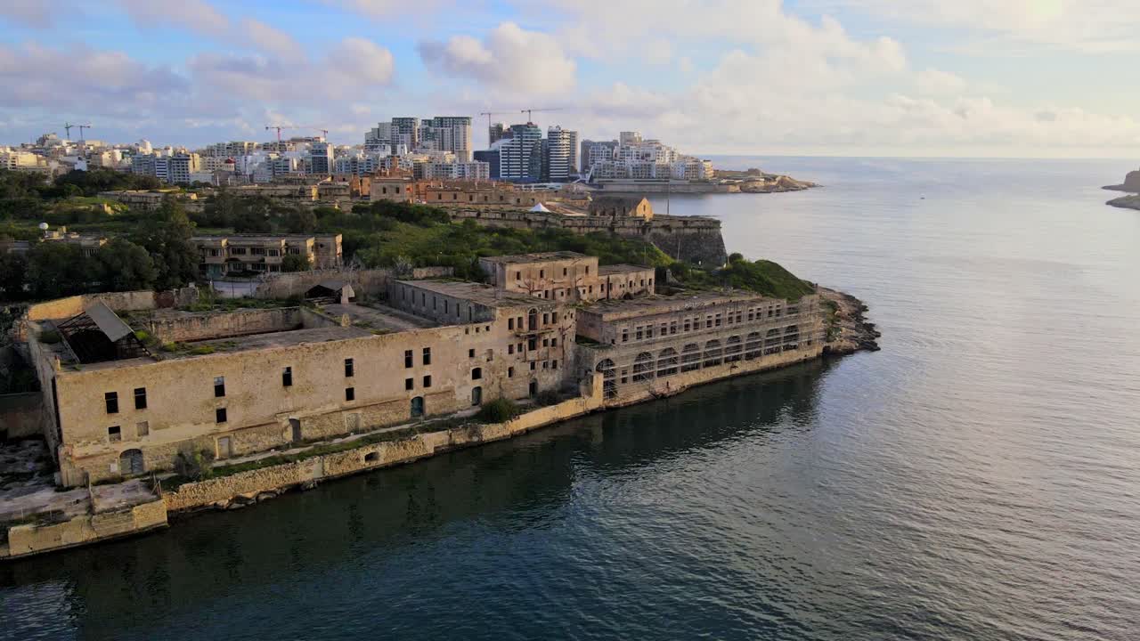 Vista aérea por drone dos edifícios abandonados de Lazzaretto na Ilha Manoel, com o horizonte moderno de Malta ao fundo