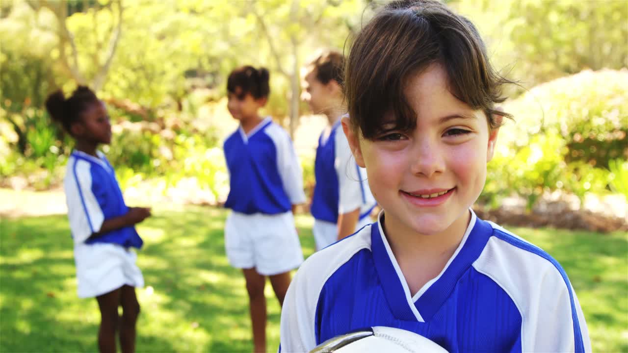 chica sonriente sosteniendo un balón de fútbol en el parque