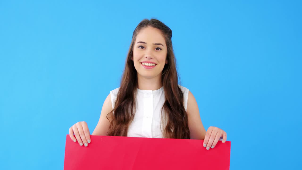 Mujer hermosa sosteniendo un cartel en blanco sobre fondo azul