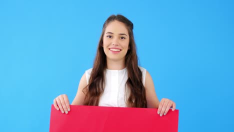 Beautiful-woman-holding-blank-placard-on-blue-background