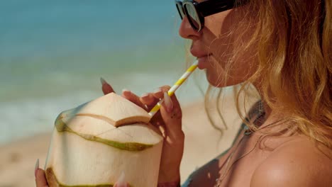Woman drinking coconut on the beach