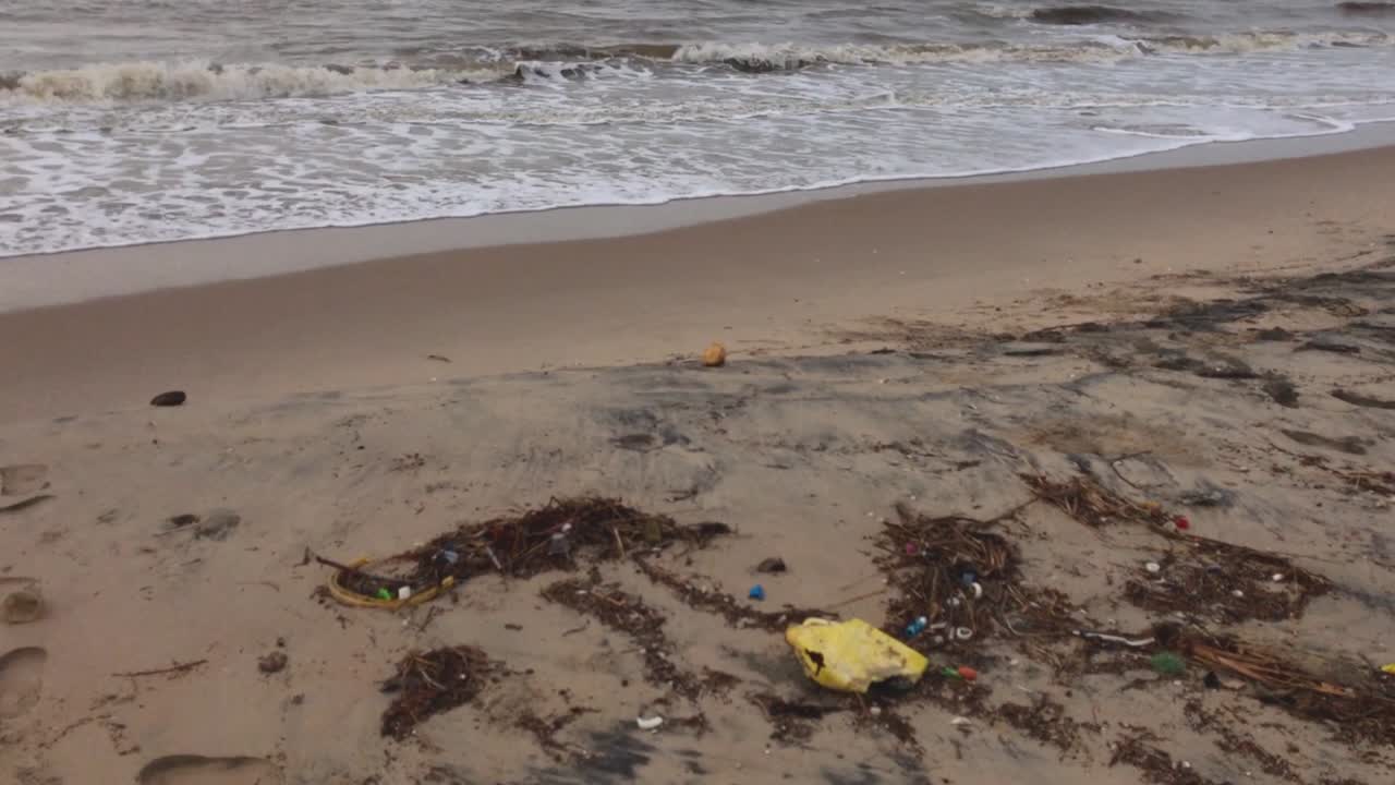 basura a la deriva en una playa de arena contaminada