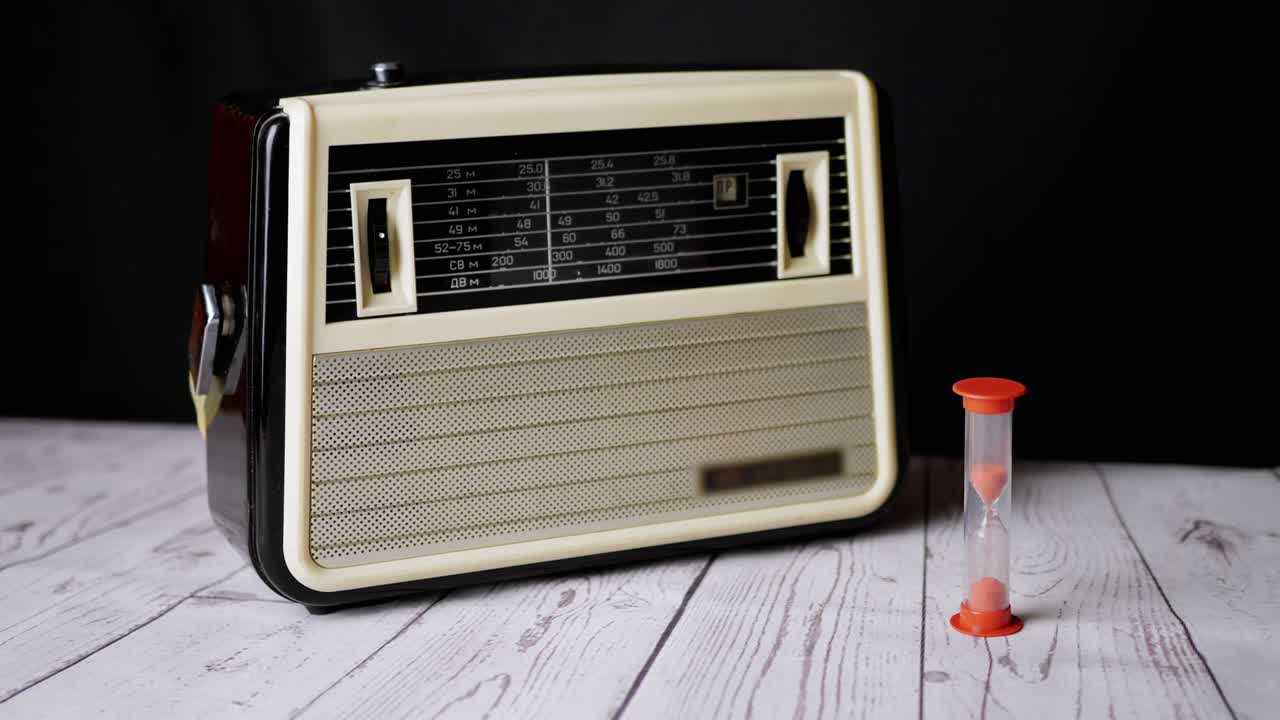 오래된 빈티지 리시버가 테이블 위에 서서 모래시계를 가지고 시간을 카운트다운하고 있습니다.