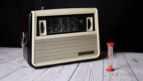 old vintage receiver standing on a table, with an hourglass counting down time