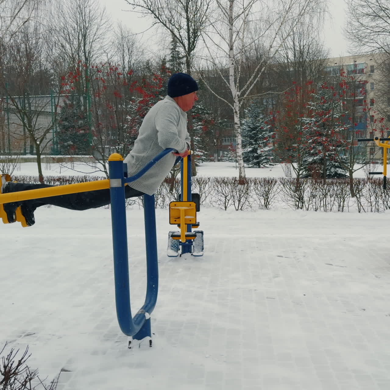 Senior man practicing healthy lifestyle. Caucasian male trains on the simulator outdoors in winter.